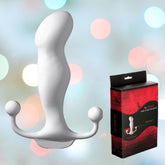 An image of the Aneros Progasm Prostate Massager - White is shown alongside its red and black packaging, which features the product image and the brand name "Aneros." This massager is designed for optimal prostate stimulation with its curved shape and handle that includes two bulbs on either side. The background is colorful and slightly blurred.